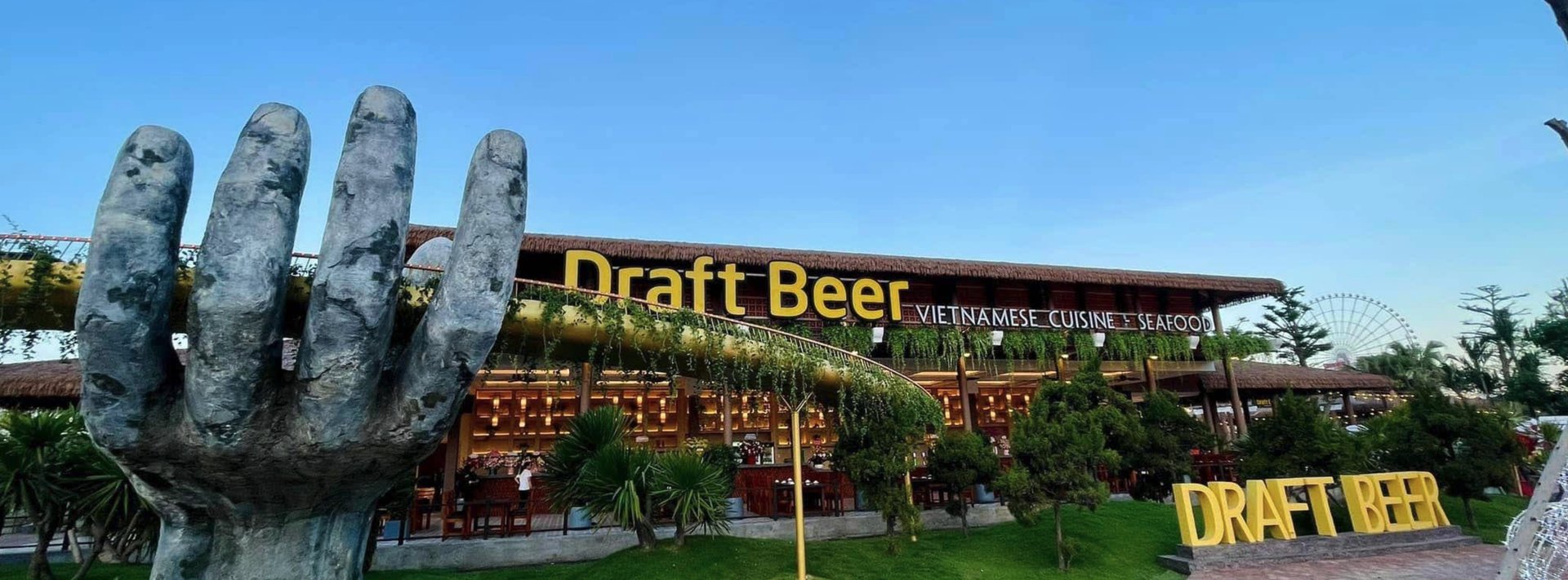 Draft Beer Danang Downtown - vườn bia và nhà hàng bên sông Hàn trên đường Bạch Đằng, Đà Nẵng, với bàn tay điêu khắc khổng lồ và vòng quay Sun Wheel phía xa